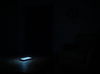 夜の暗い部屋。低いテーブルの上でスマートフォンだけが光っていて、そのそばの椅子には誰も座っていない