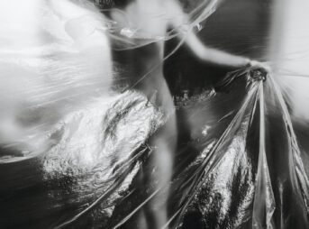 a black and white photo of a woman wrapped in plastic